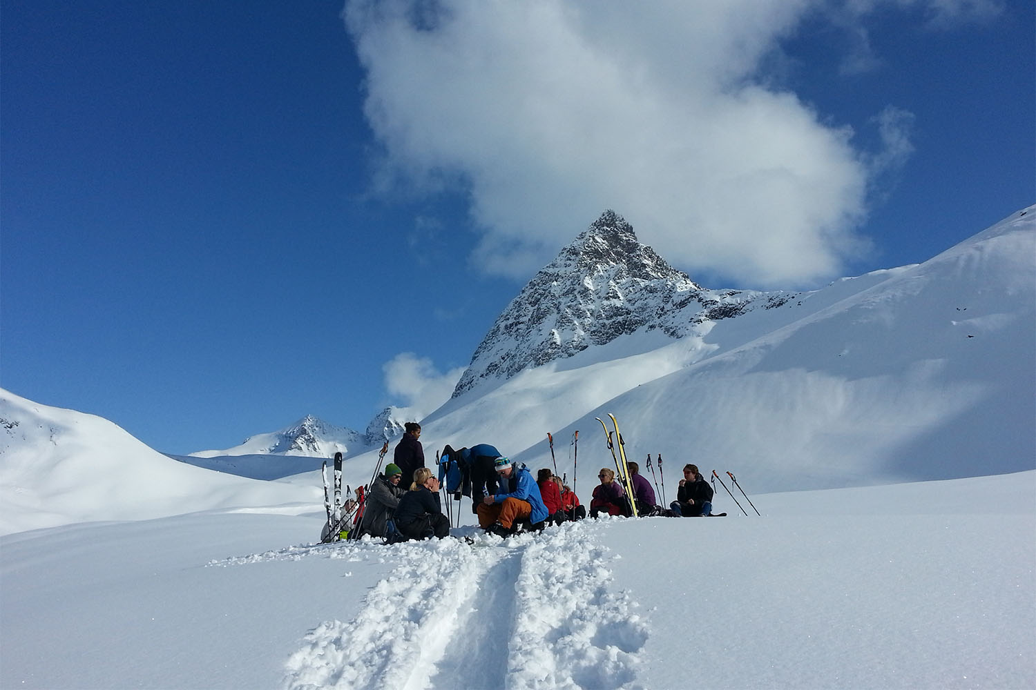 Fleire skigåarar kviler i snøkledd skibakke, på fjellet med Slogen i bakgrunnen.