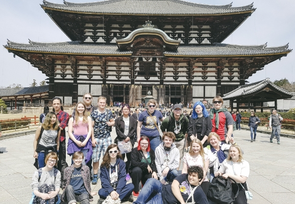 Ei gruppe studenter i gruppebilde foran eit asiatisk tempel