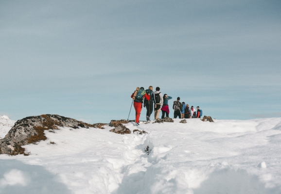 Ei rekke med fleire skigåarar på vei over eit snøkledd fjell