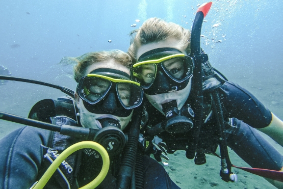 Undervannsbilde av to dykkarar som ser mot kamera