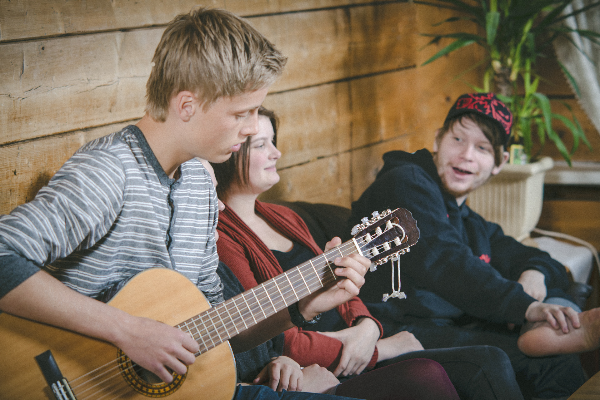 Ein gut sit og spelar gitar saman med to medelevar på internatet på Møre Folkehøgskule