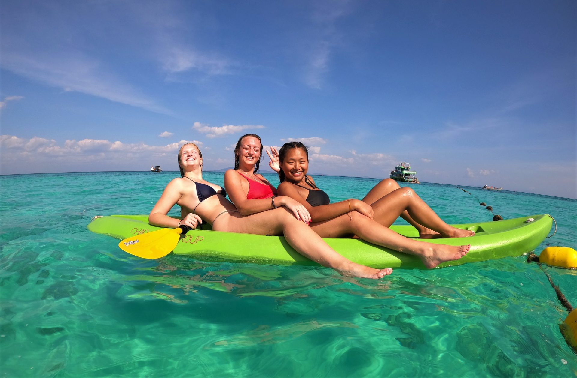 Tre jenter sit saman i ein kajakk på vatnet