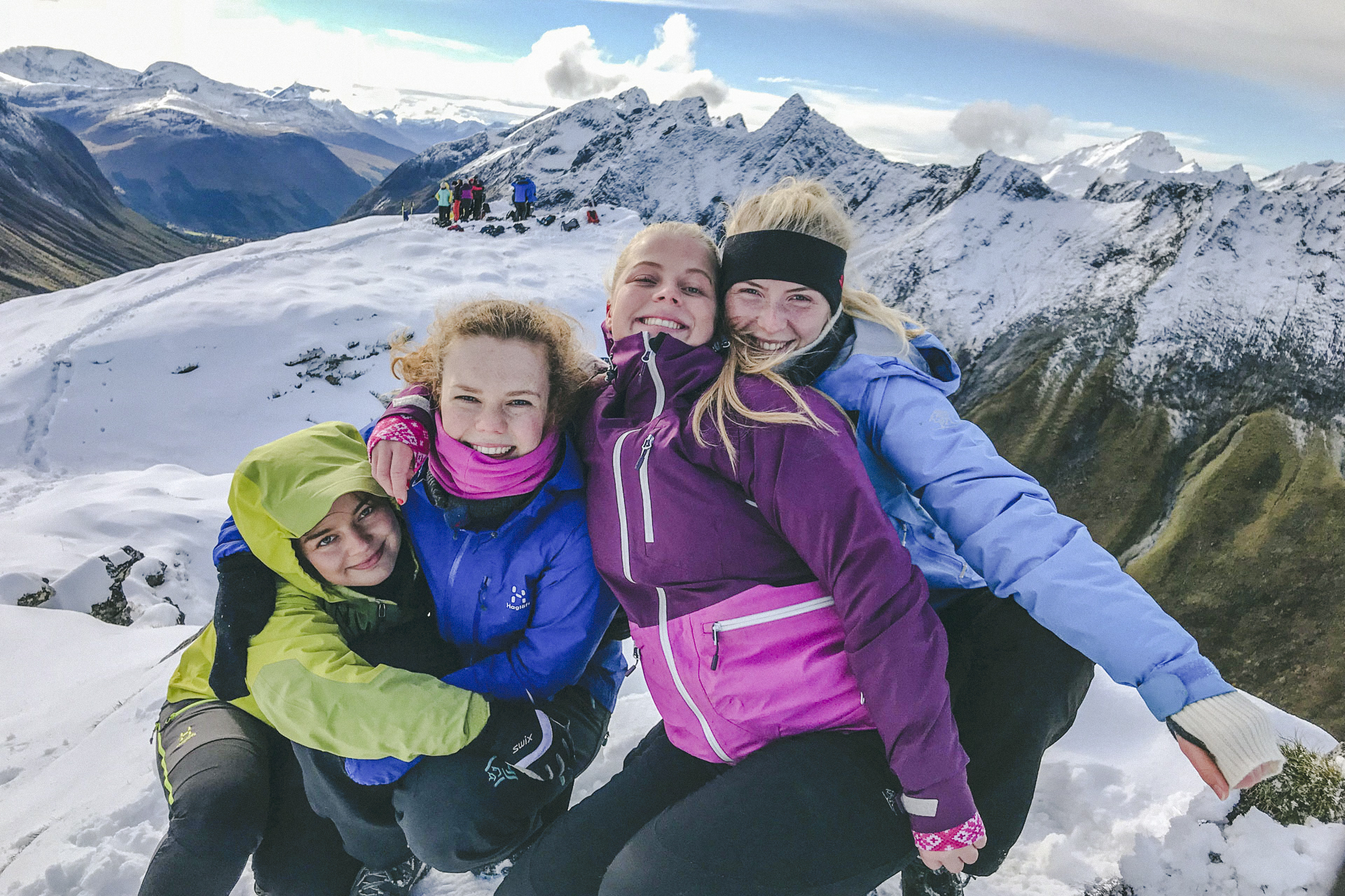 Tre jenter frå Friluftsliv linja poserar saman på eit snøkledd fjell